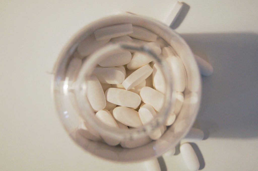 A picture of white pills in a bottle.