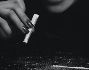 Black and white picture of a hand holding a rolled dollar bill above a line of cocaine.