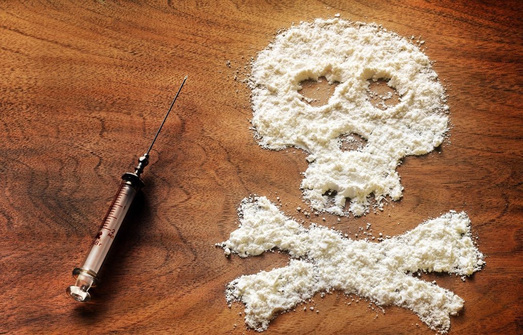 Cocaine spread in the shape of a skull with a syringe next to it