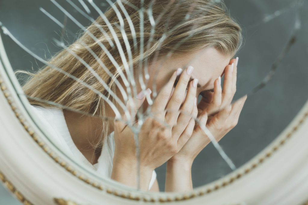 a girl standing in front of a broken mirror