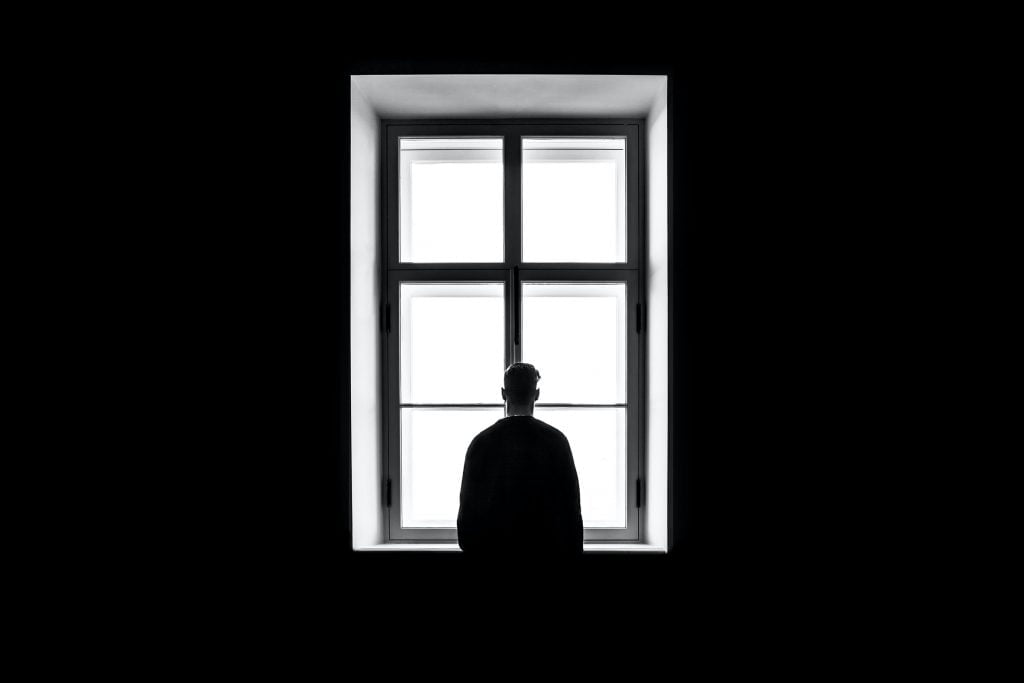 Man standing in a dark room in front of a window.
