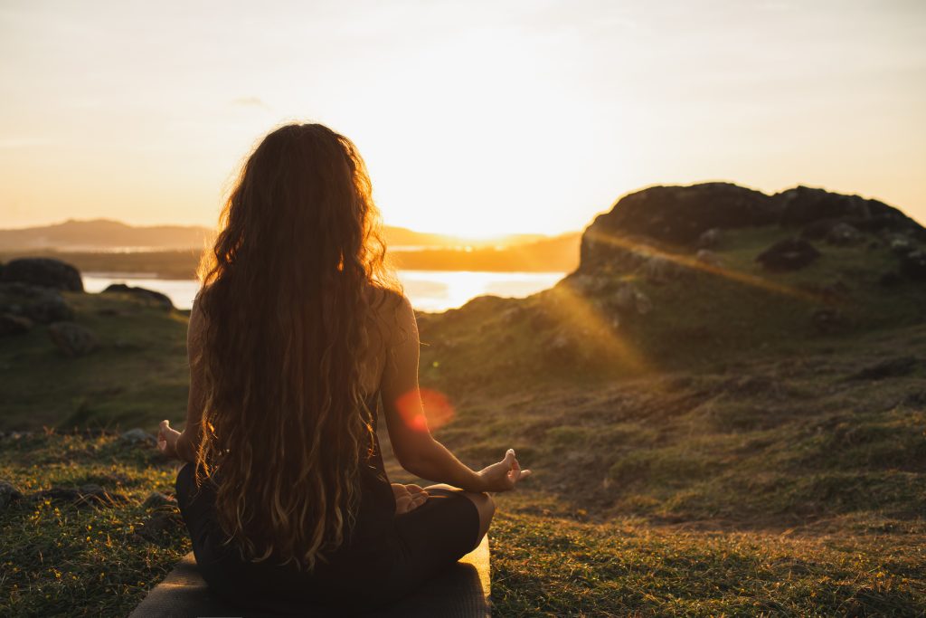 woman meditating with a beautiful view in the background