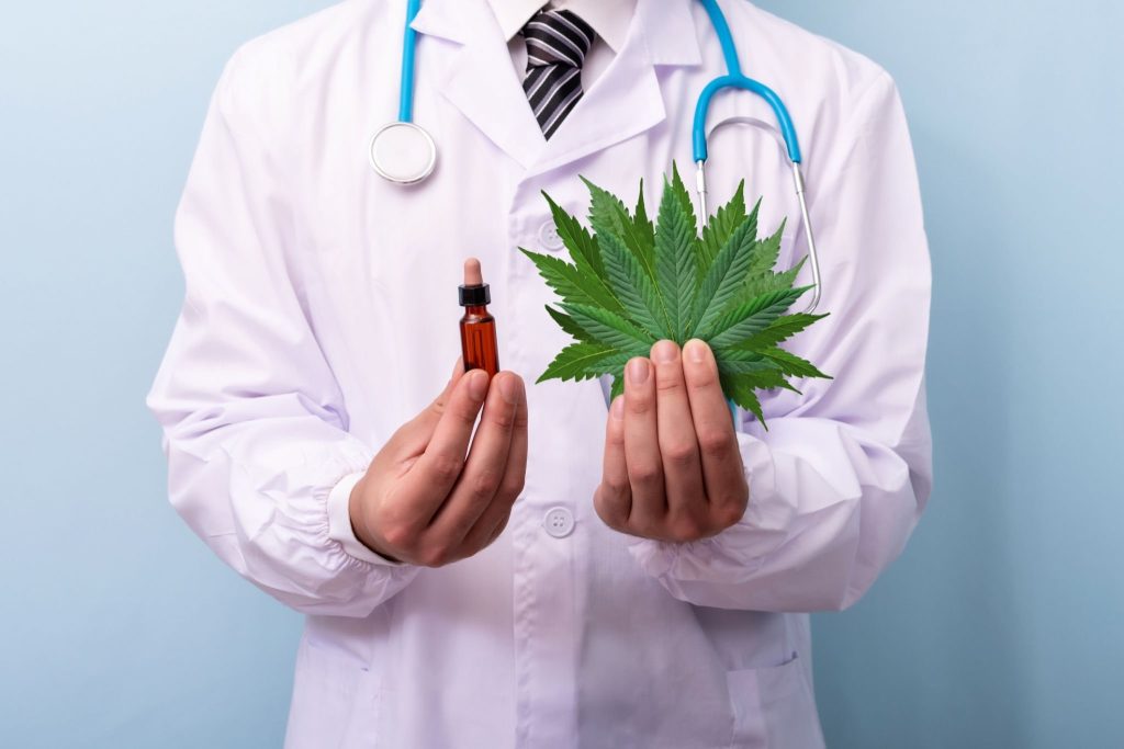 doctor holding a leaf of marijuana