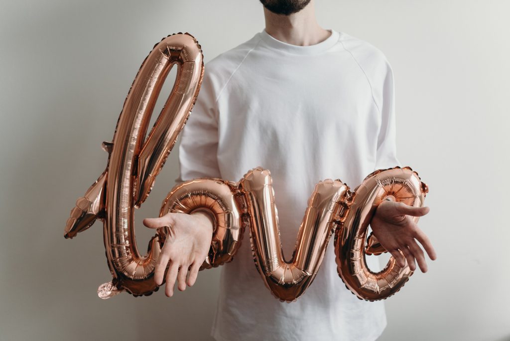 A person with his hands stuck in a balloon that spells the word Love.