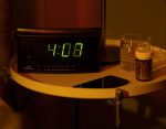 Clock displaying 4:08 with a bottle of pills next to it.