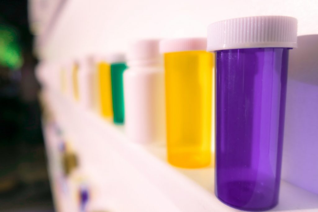 Empty colorful pill bottles on a shelf.