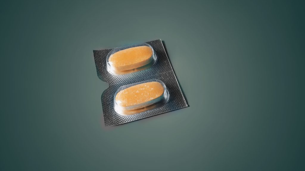 Two orange pills with a green background.