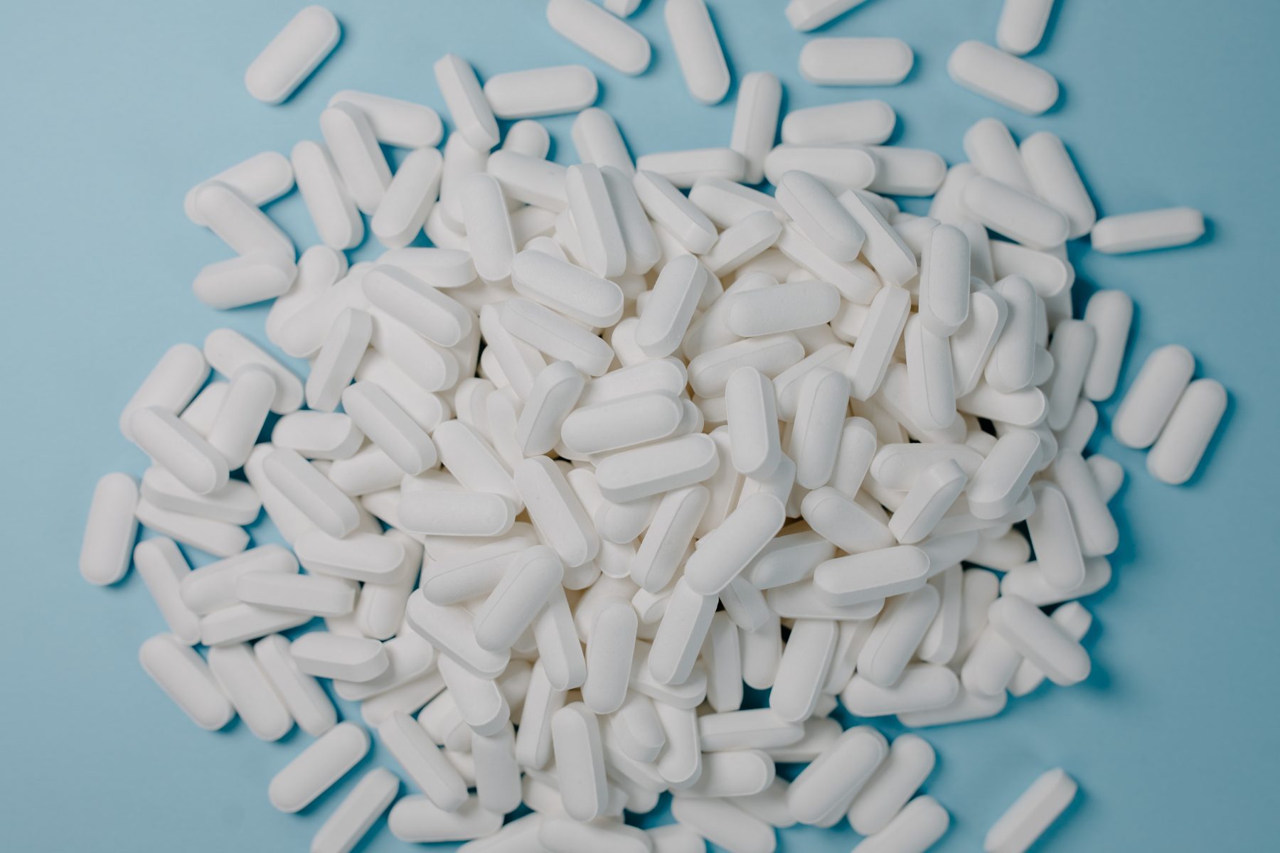 A bunch of white pills with a blue background.