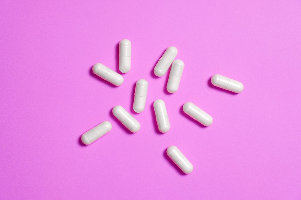 White pills on a pink background.